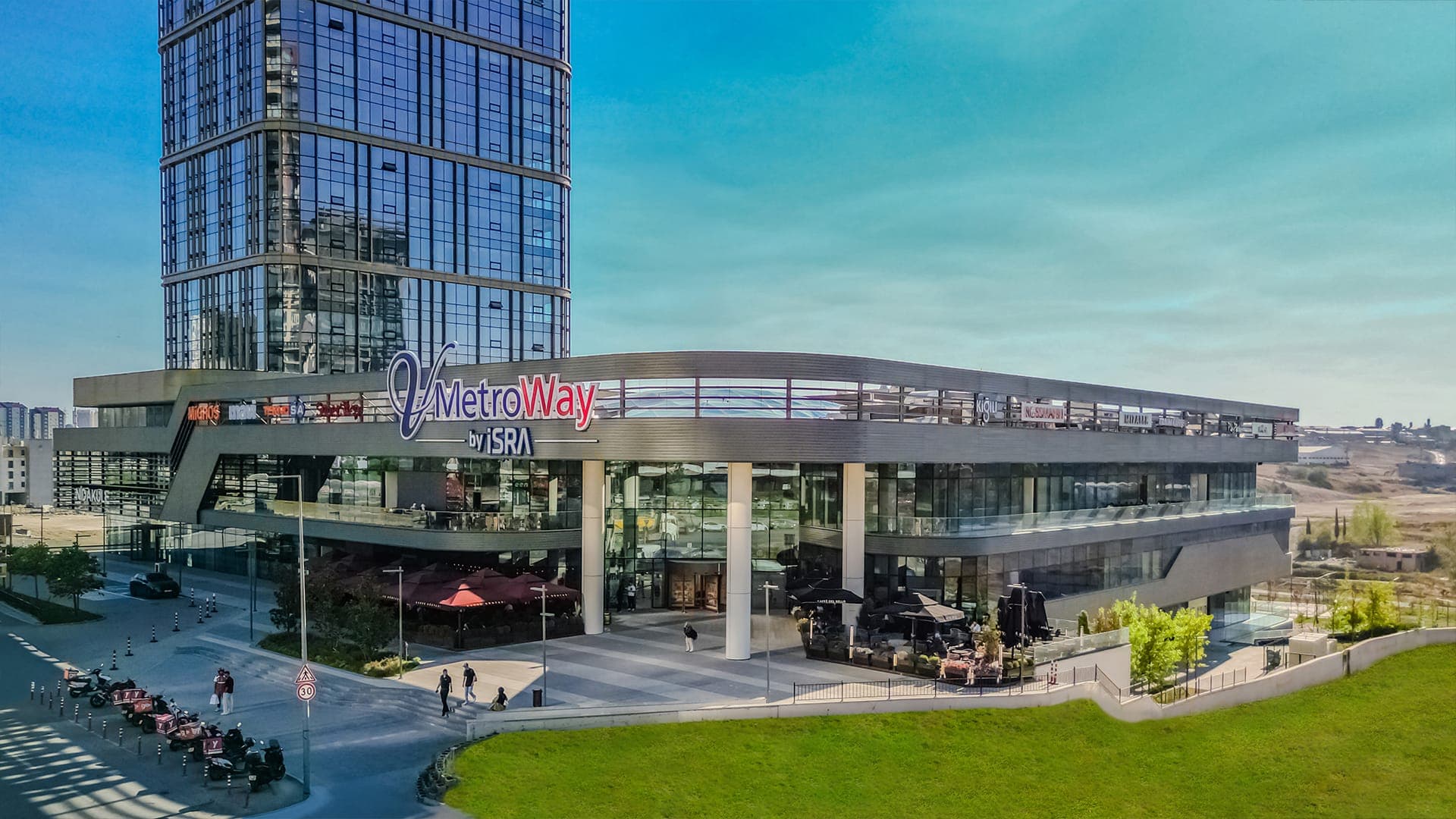 V Metroway'in yeşil alandan görünen dış cephesi ve çatı tabelası